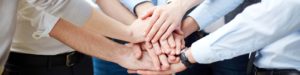 Hands clasped together in the centre of a group of people.
